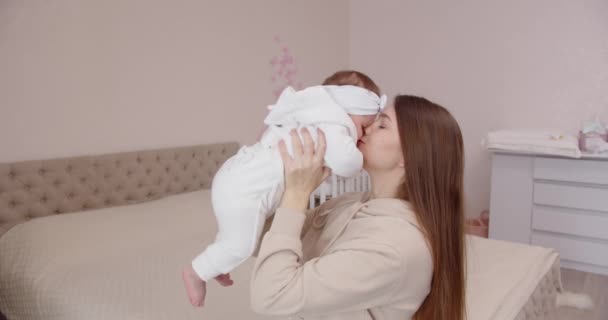 Glückliche junge Mutter streichelt ihr Neugeborenes zärtlich und hält es auf dem Arm — Stockvideo