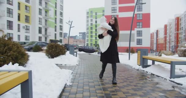 Liebevolle Mutter geht im Winter mit Baby auf der Straße — Stockvideo