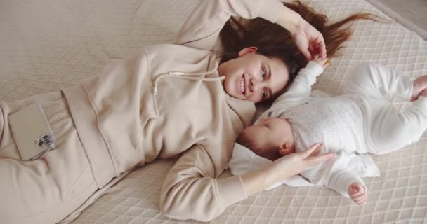 Mladá matka hoří s dítětem ležícím na posteli — Stock video