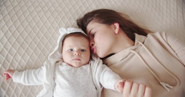 Newborn baby holds moms hand while lying on the bed — Stock Video