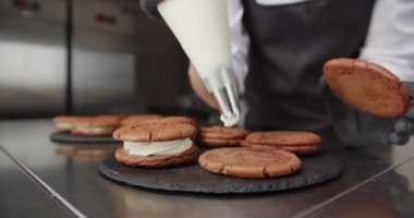 Pasta koluyla, kurabiyelere krema sür. Tatlılar yap