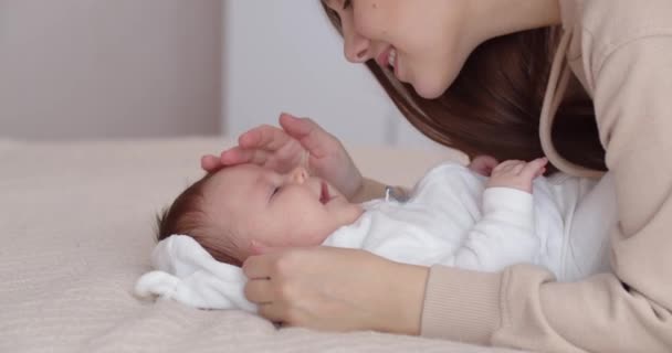 Турботлива мати доглядає за новонародженою дитиною, м'яко цілує її і гладить обличчя — стокове відео