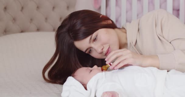 Mamãe se deita na cama com o bebê e o acalma — Vídeo de Stock