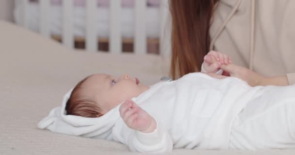 Una madre se inclina sobre su bebé recién nacido acostado en la cama — Vídeos de Stock
