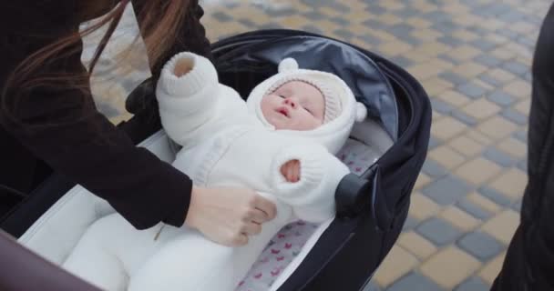 Mamá pone a una niña recién nacida en un cochecito en un paseo — Vídeo de stock