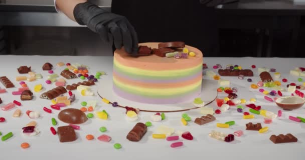 A cukrász édes cukorkával díszíti az ünnepi tortát. — Stock videók