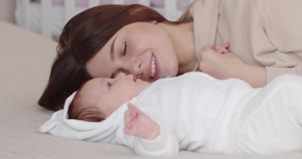 Материнская любовь. Заботливая мать улыбается новорожденному ребенку — стоковое видео