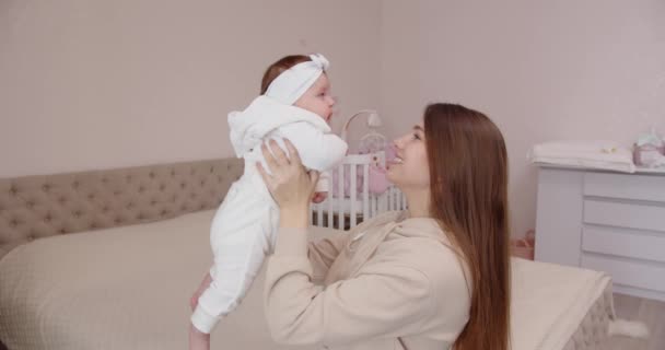 Glückliche junge Mutter streichelt und küsst das Neugeborene zärtlich und hält es in ihren Armen — Stockvideo