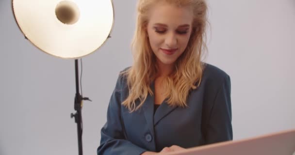 Ragazza che lavora su un computer portatile in studio su uno sfondo bianco — Video Stock