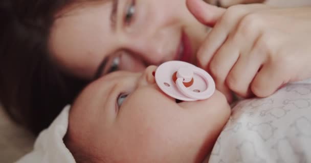 Mamãe se deita na cama ao lado do bebê e o acalma — Vídeo de Stock