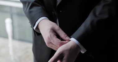 Adam zarif siyah bir takım giyiyor.