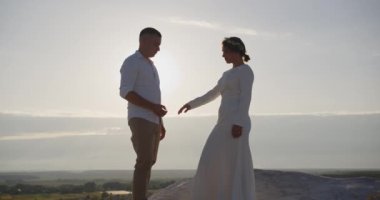 Newlyweds Beautiful young joyful bride and groom walking on the mountain slope. Wedding couple. Happy family. Man and woman in love. The bride in a chic wedding dress. Slow motion