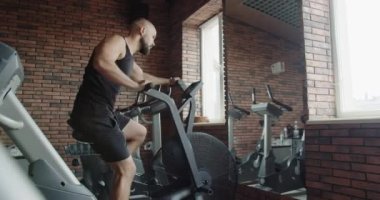 A person pedals on an exercise bike in a gym. Cardio training, pumping leg muscles