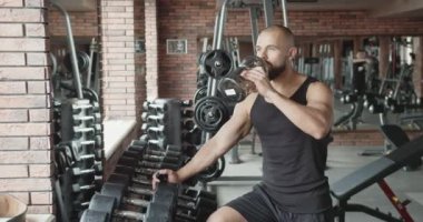 Spor salonunda kas yapan bir adam. Çekici erkek görünüşü. Kas büyütme. Spor besinleri, biyolojik takviyeler.