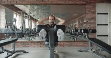 Bir adam spor salonundaki simülatörde sırt ve karın kasları için egzersiz yapıyor, vücudunu geliştiriyor. Kardiyo eğitimi. Güçlendirme egzersizleri. Kas oluştur