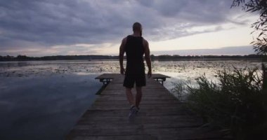Yakışıklı genç adam kumlu deniz sahilinde sabah yogası yapıyor. Yavaş çekim