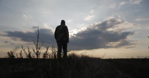 一名士兵日落时穿过田野 环顾四周 看到一名身穿制服的军人在守卫着 保护着平民 — 图库视频影像