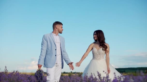 新婚燕尔 恋爱中的新婚夫妇 漫步在一片鲜花的田野里 — 图库视频影像