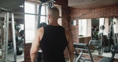 Spor salonundaki bir sporcu kaslarını şişiriyor.