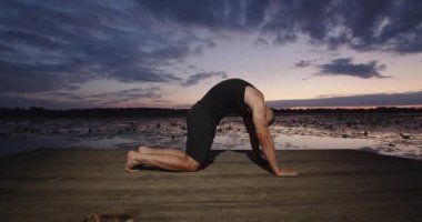 Bir erkek vücut kaslarını germek için egzersiz yapar.