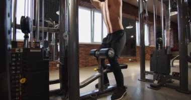 Sporcu vücut geliştirici spor salonunda antrenman yapıyor. Ağırlık kaldırma, vücut geliştirme, kas güçlendirme eğitimi. Bir adam simülatörde egzersiz yapar. Geri çekilmeyi öğreniyorum.