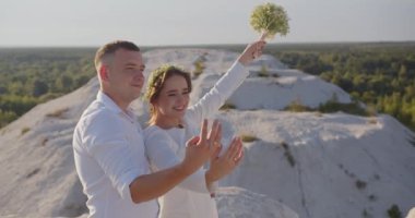 Düğün çifti. Damat gelini kucaklıyor. Gelin ve damat dışarıda yürüyor. Aşık bir adam ve kadın. Güzel gelin ve damat. Düğün günü. Gelin elinde bir buket düğün çiçeği tutuyor.