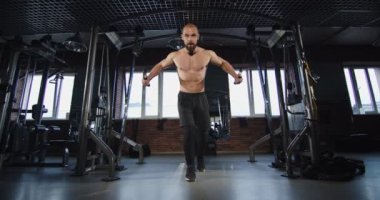 Genç bir atlet simülatörde ağır bir ağırlıkla göğüs ve sırt kaslarını çalıştırır.