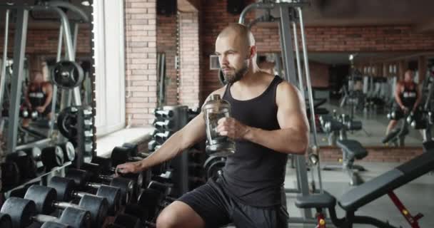 男はジムでスポーツシミュレーターに取り組み 体を改善します 心臓訓練だ 筋力トレーニング — ストック動画