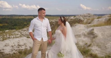 Düğün çifti. Damat gelini kucaklıyor. Gelin ve damat dışarıda yürüyor. Aşık bir adam ve kadın. Güzel gelin ve damat. Düğün günü. Gelin elinde bir buket düğün çiçeği tutuyor.