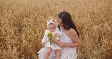 Genç ve mutlu bir anne küçük bir bebekle yürüyor.