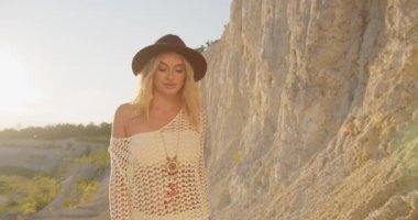 Kız taşlarla kaplı sahilde yürüyor.