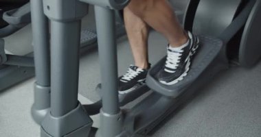 Spor salonunda spor simülatörleri üzerinde çalışan bir adam vücudunu geliştiriyor. Kardiyo eğitimi. Kuvvet egzersizleri