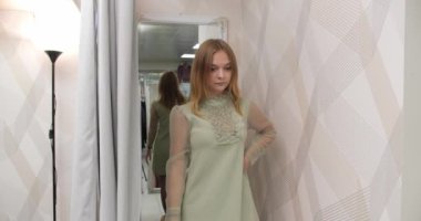 Kız soyunma odasından çıkar ve aynada kendine bakar.