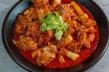 Kore yemeği Baharatlı Karıştırılmış Kızarmış Tavuk tteokbokki siyah tabakta