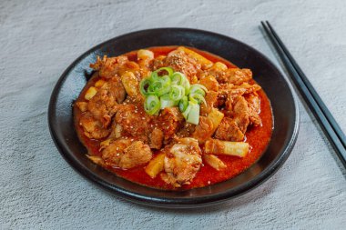 Kore yemeği Baharatlı Karıştırılmış Kızarmış Tavuk tteokbokki siyah tabakta