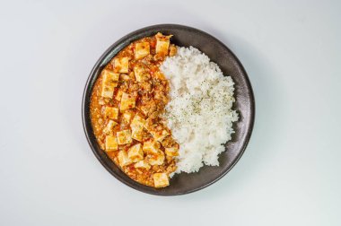 Çin yemeği mapo tofu yemeği ve siyah tabakta pirinç.