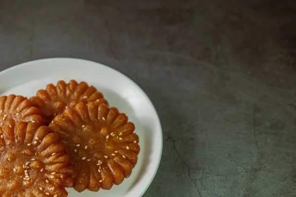 Yakgwa, Korean style honey cookie : Flour mixed with honey and sesame oil, pressed in a yakgwa pan (yakgwa mold), shallow-fried or deep-fried, dipped in grain syrup or honey, and sprinkled with chopped pine nuts.