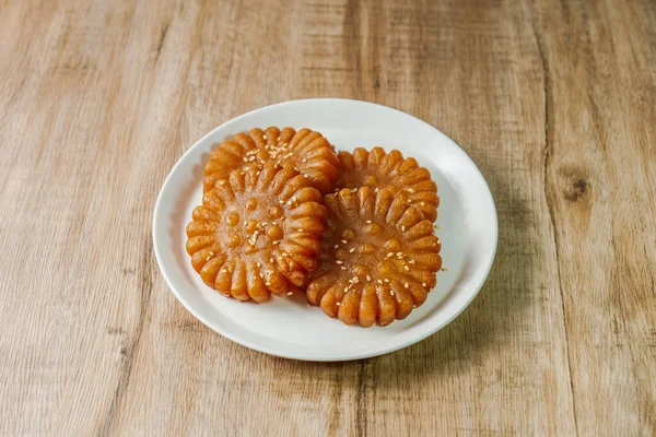 Yakgwa, Korean style honey cookie : Flour mixed with honey and sesame oil, pressed in a yakgwa pan (yakgwa mold), shallow-fried or deep-fried, dipped in grain syrup or honey, and sprinkled with chopped pine nuts.