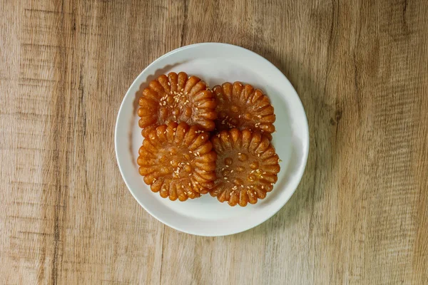 Yakgwa, Korean style honey cookie : Flour mixed with honey and sesame oil, pressed in a yakgwa pan (yakgwa mold), shallow-fried or deep-fried, dipped in grain syrup or honey, and sprinkled with chopped pine nuts.