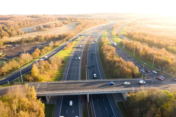 Aerial view of a UK Motorway and overpass bridge through picturesque countryside at sunset