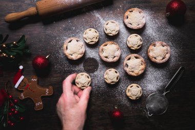 A home baking concept of traditional Christmas mince pies arranged in the shape of a Christmas Tree and covered in icing sugar
