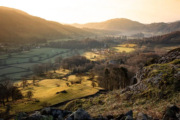 Sabahın erken saatlerinde, Grasmere köyünün güneş ışığı ve fotokopi uzayı boşluklarıyla Lake District Nation Park 'taki manzarası.