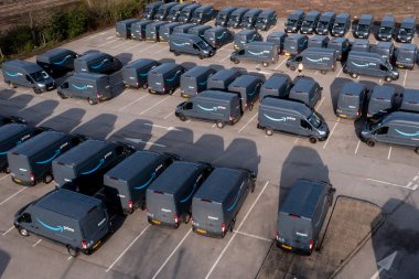 Leeds, İngiltere - 15 Nisan 2022. New Amazon Prime Ford E-Transit elektrik dağıtım kamyonlarının hava görüntüsü daha az emisyonlu ürünler için nakledilmeye hazır