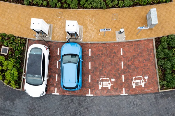 An aerial view directly above electric cars being charged at a motorway service station car charging station