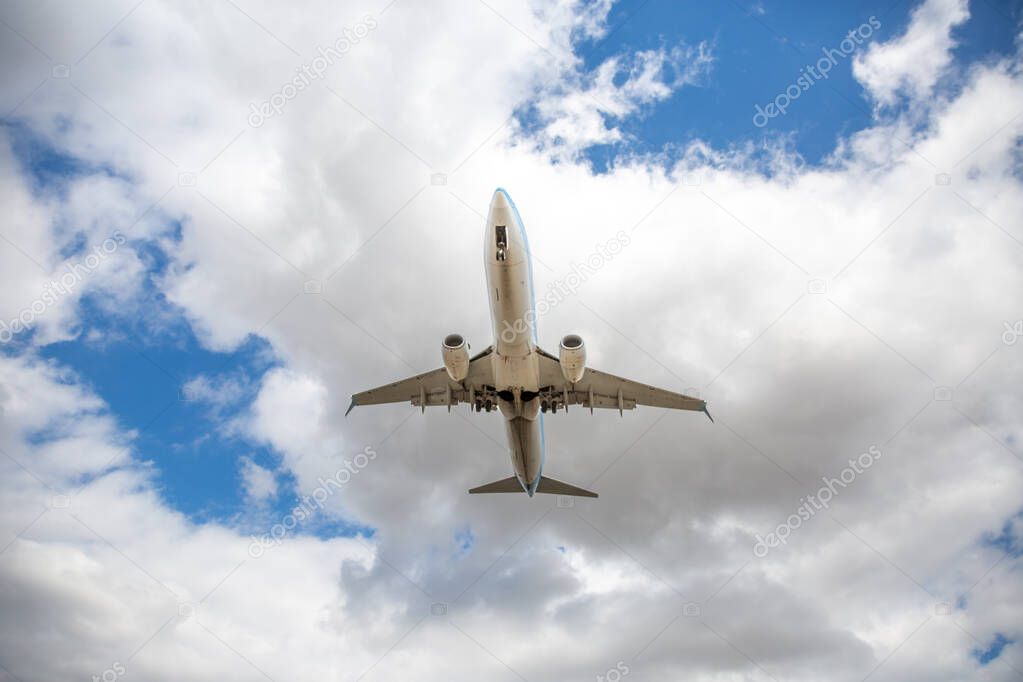 A low angle view directly below a TUI aircraft with clouds above and copy space on take off