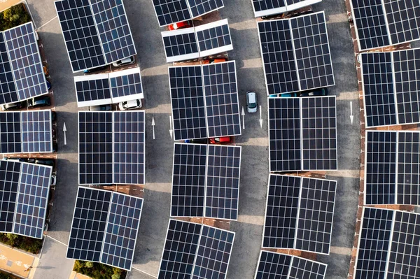 Aerial view directly above electric cars parking under solar panels on a parking lot rooftop ready for charging