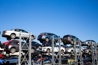 DERBY, UK - AUGUST 11, 2022.  Profile view of scrap motor cars involved in road traffic accidents stacked up on racks in a scrap metal dealers yard with copy space