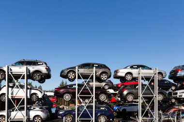 DERBY, UK - AUGUST 11, 2022.  Profile view of scrap motor cars involved in road traffic accidents stacked up on racks in a scrap metal dealers yard with copy space