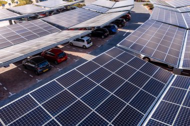 LEEDS, UK - AUGUST 19, 2022. Aerial view above innovative solar panels located on a car parking lot rooftops making good use of small space in a city and providing sustainable energy for electric vehicle charging