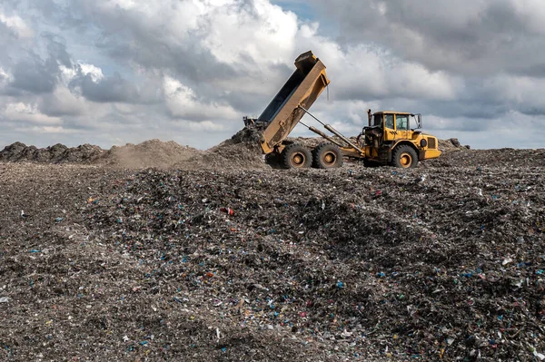 A dumper truck on a large waste management landfill site dumping rubbish in an environmental issue image